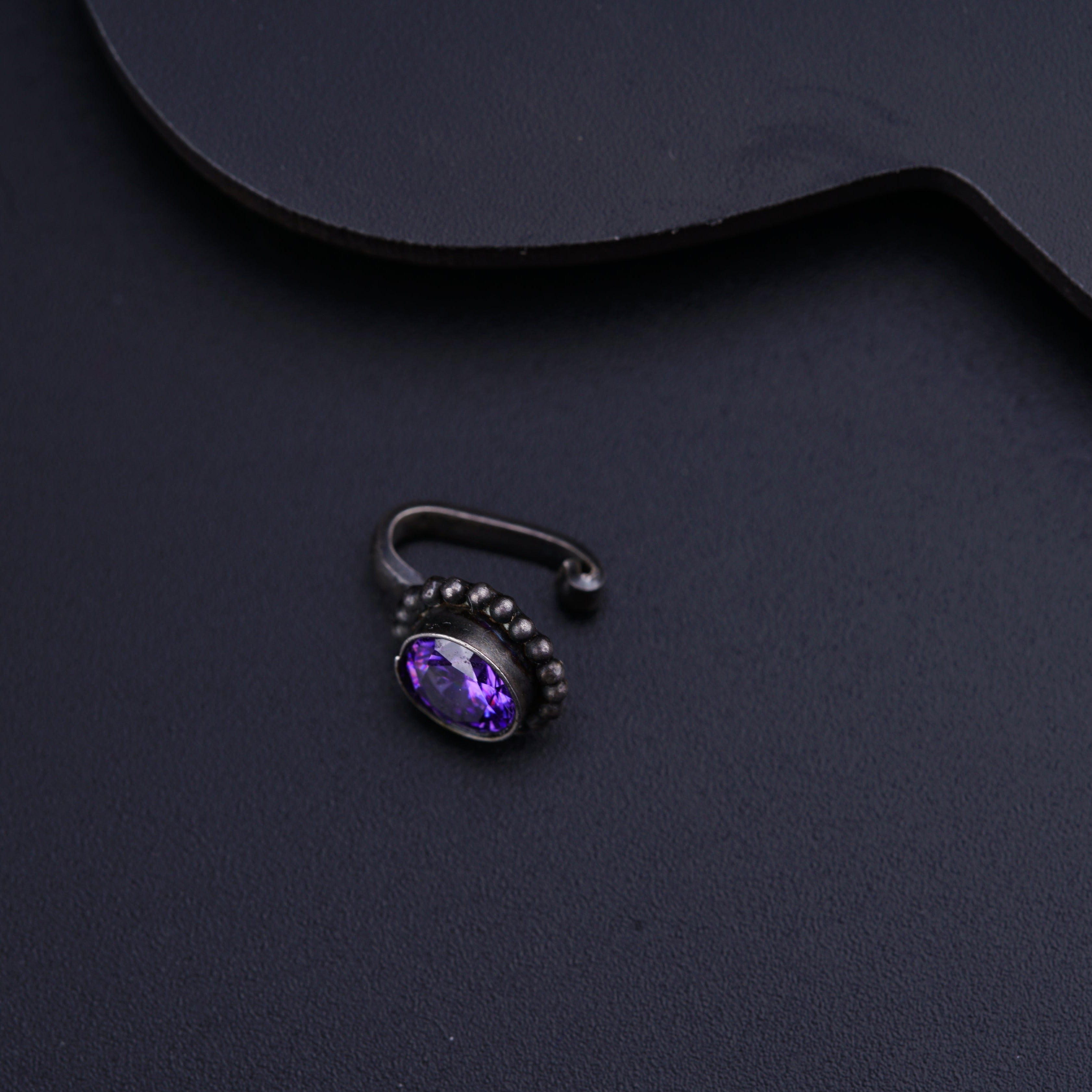 a purple stone ring sitting on top of a black surface