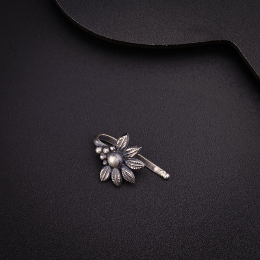 a brooch with a flower on it sitting on a black surface