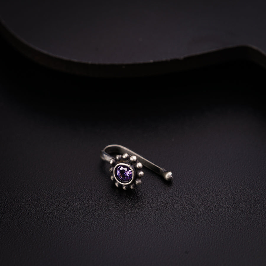 a ring with a purple stone is sitting on a black surface