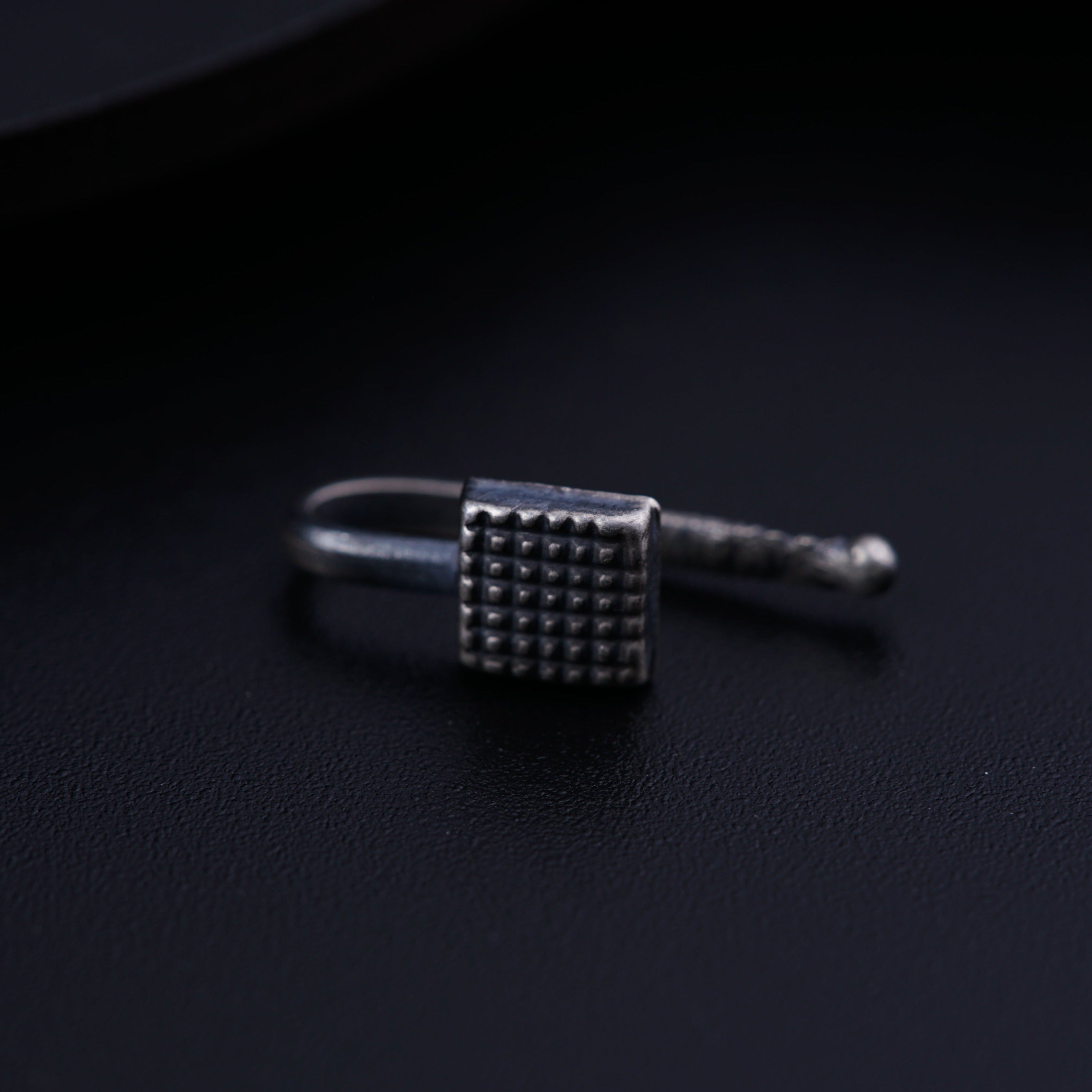 a ring with a square design on a black surface