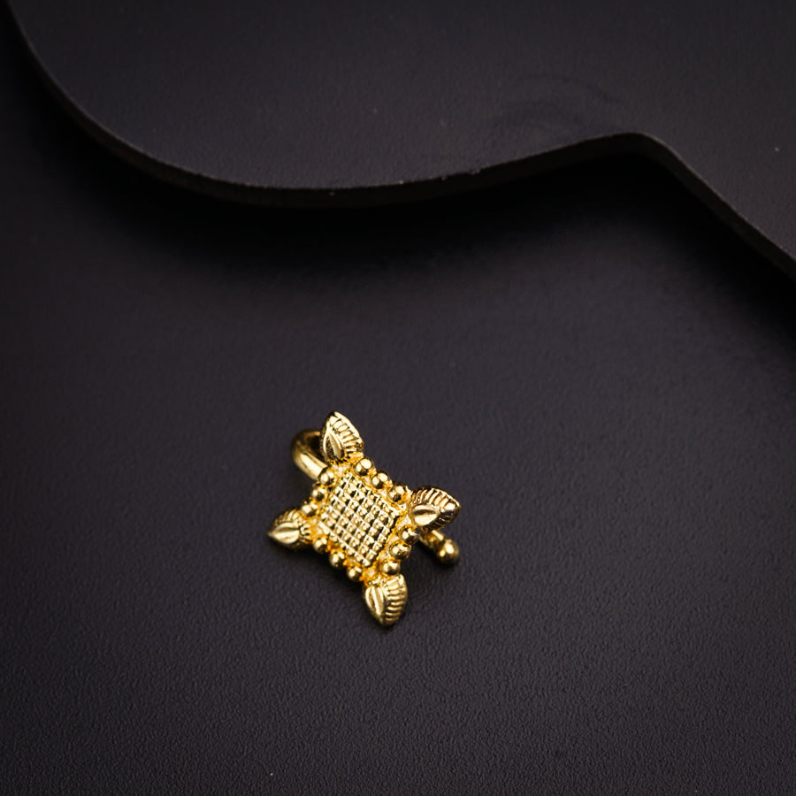 a gold plated metal object on a black surface