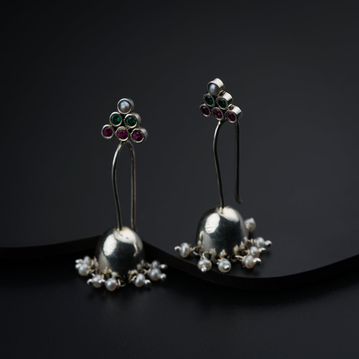 a pair of silver earrings with flowers and pearls