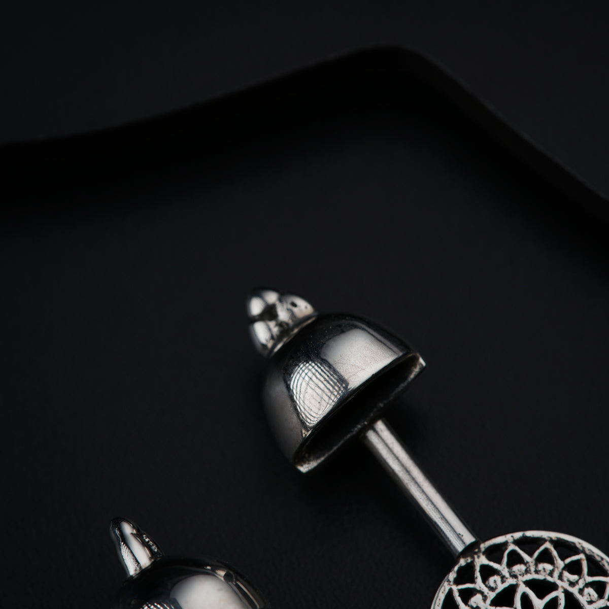 a pair of silver bells on a black surface