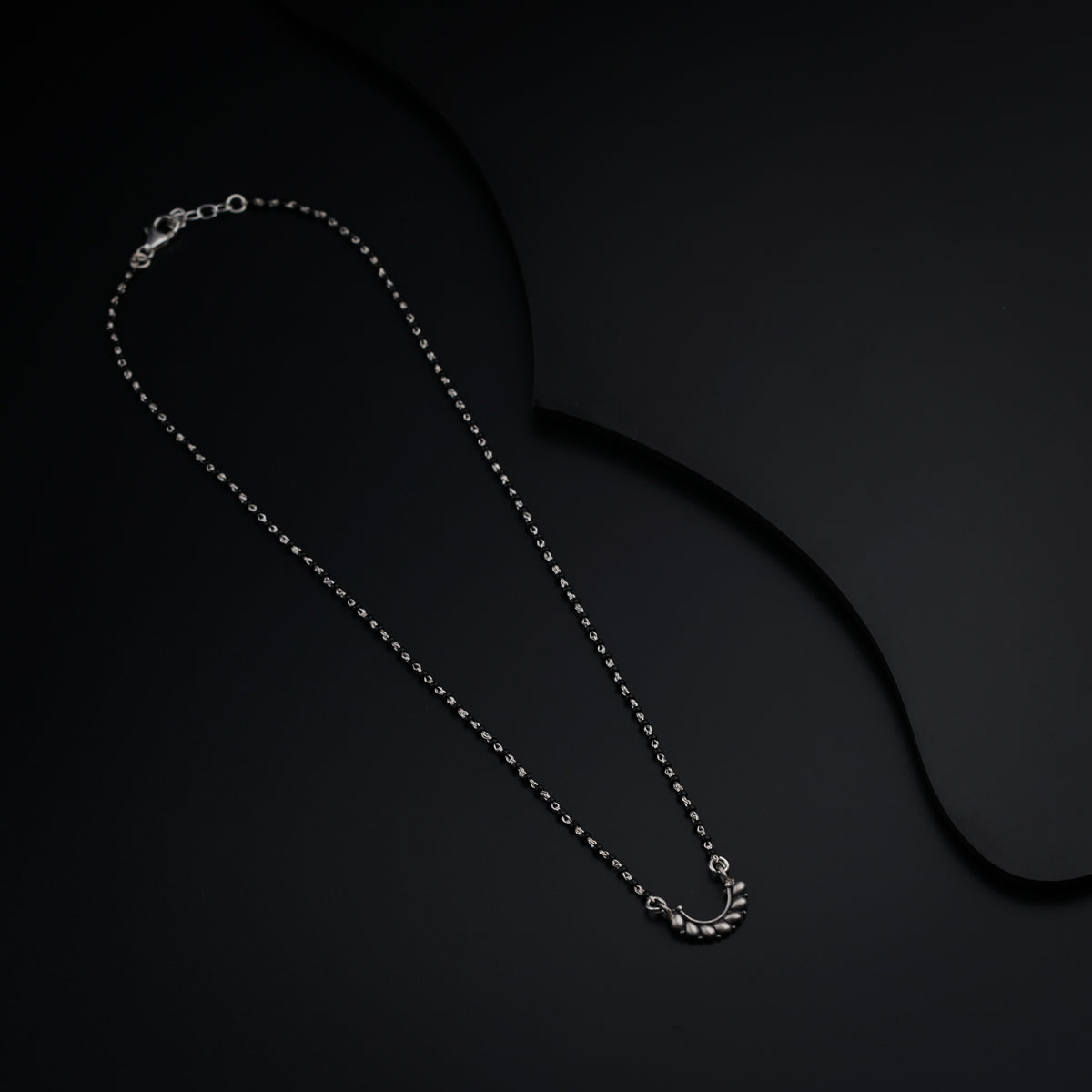 a black background with a silver necklace on it