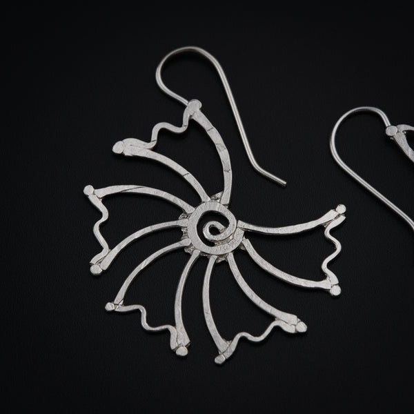 a pair of silver earrings on a black surface