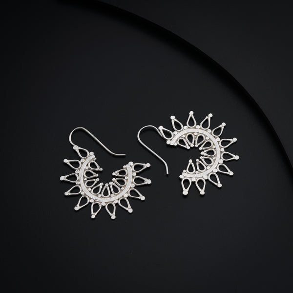 a pair of white earrings sitting on top of a black surface