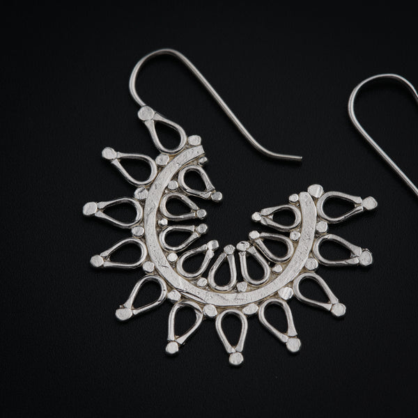 a pair of silver earrings on a black background