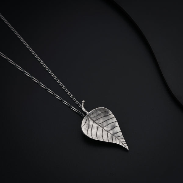 a silver necklace with a leaf on it