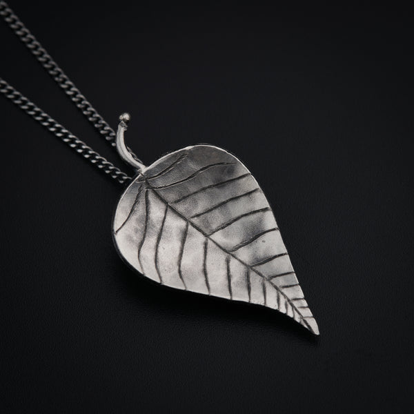 a silver leaf pendant on a black background