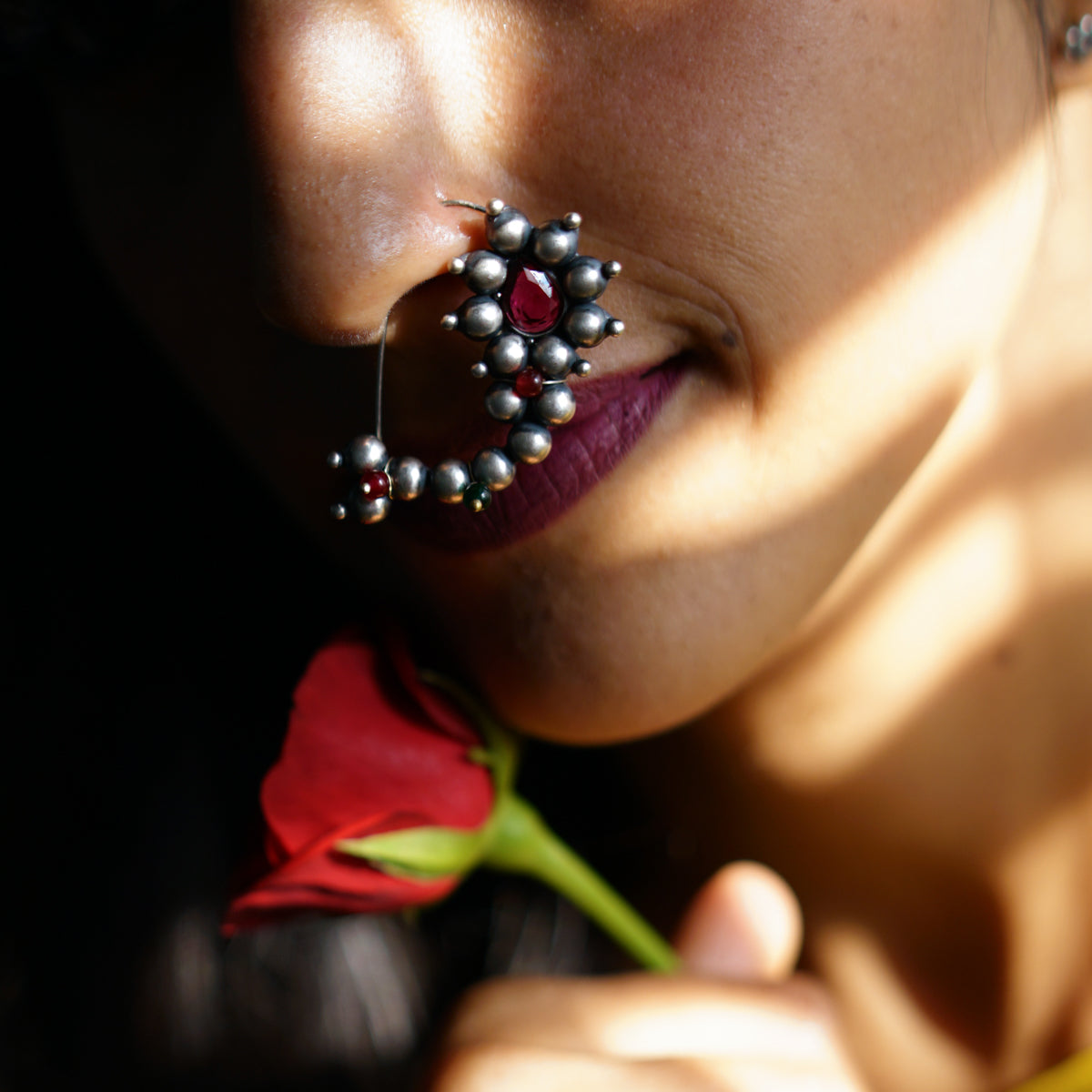 a close up of a woman with a flower in her nose