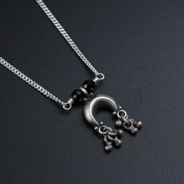 a silver necklace with a black bead hanging from it
