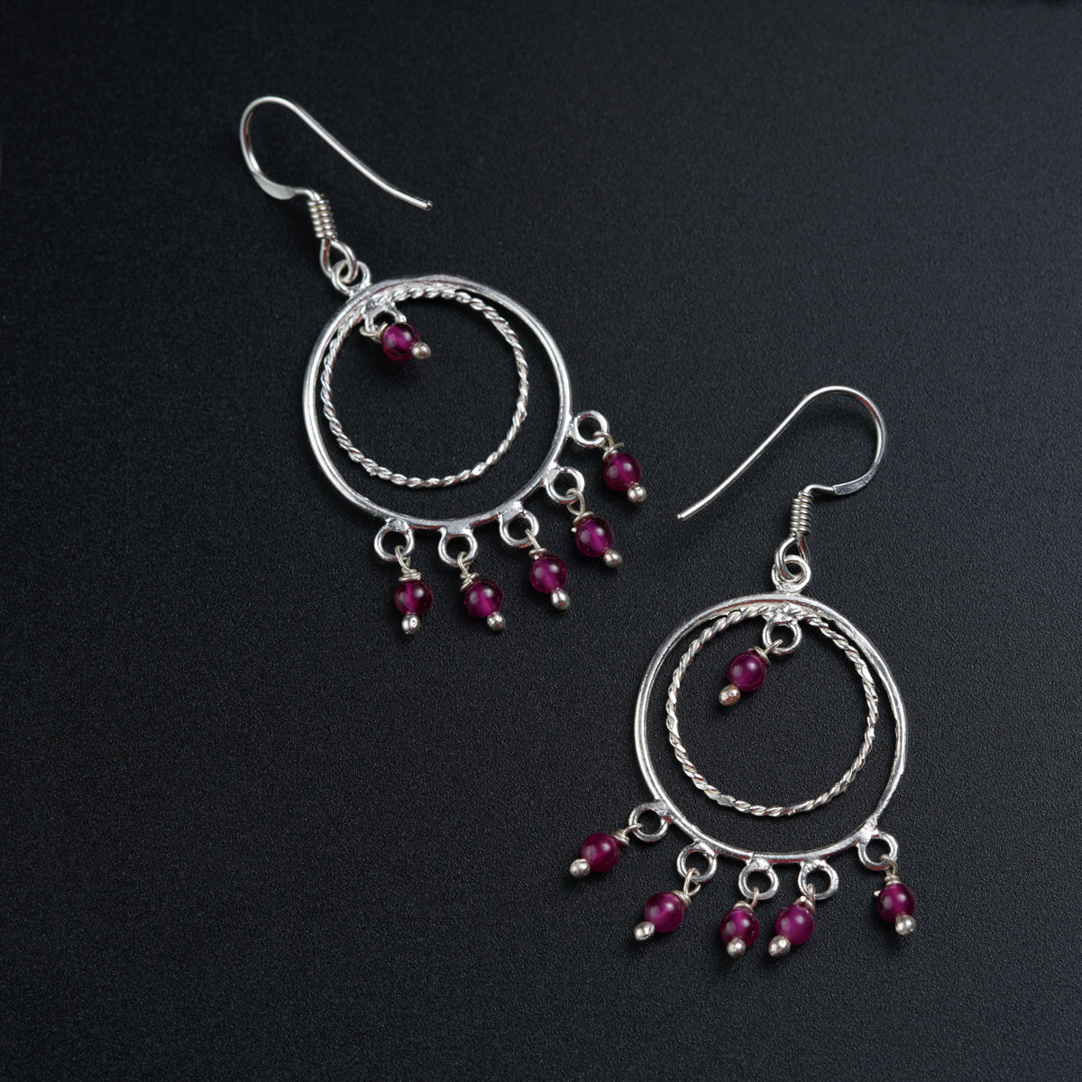a pair of silver hoop earrings with red beads