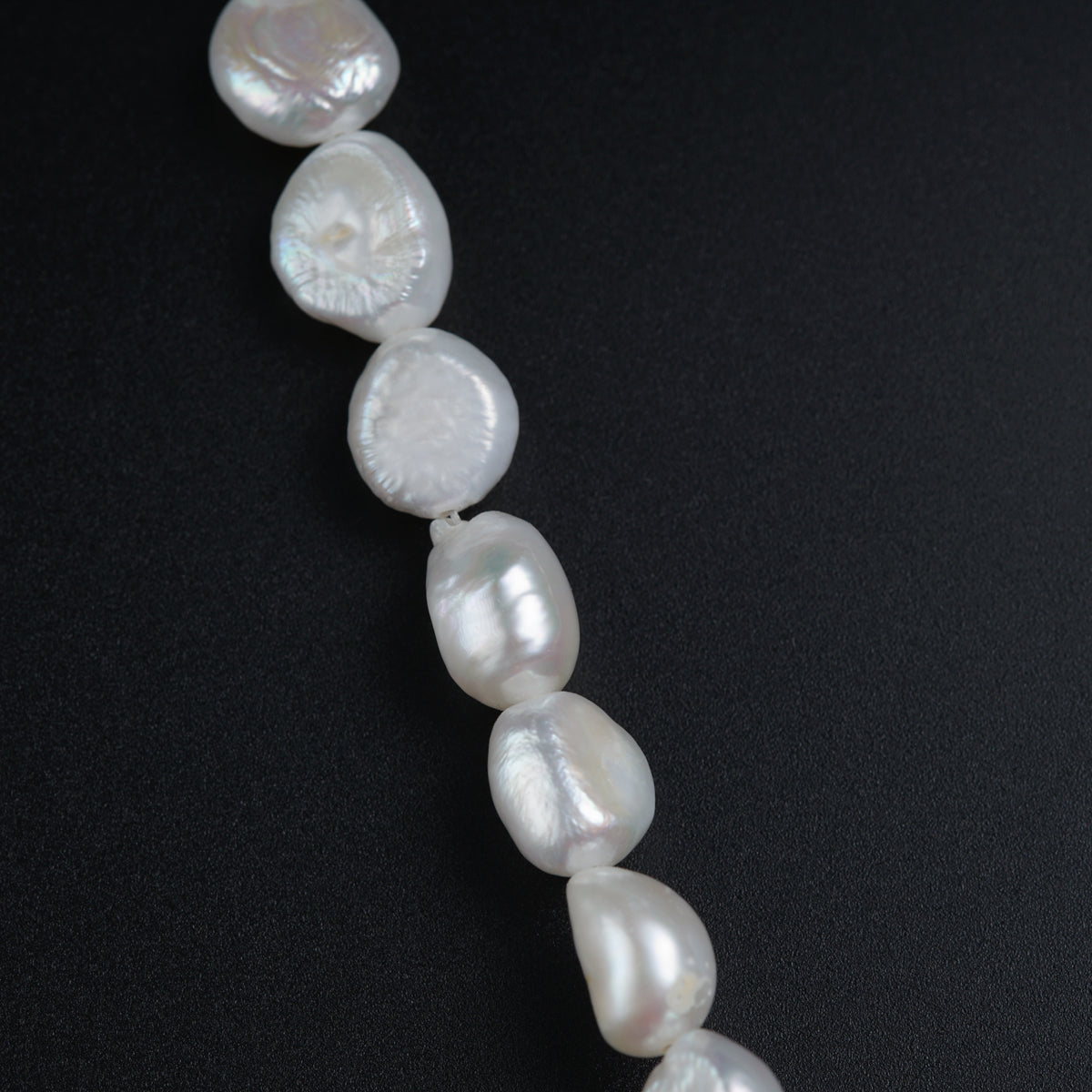 a long strand of white pearls on a black surface
