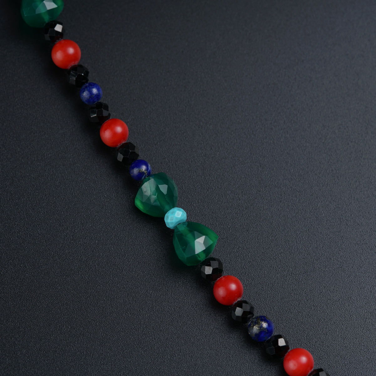 a long beaded necklace on a black surface