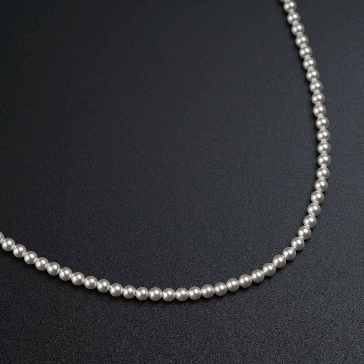 a single strand of pearls on a black surface