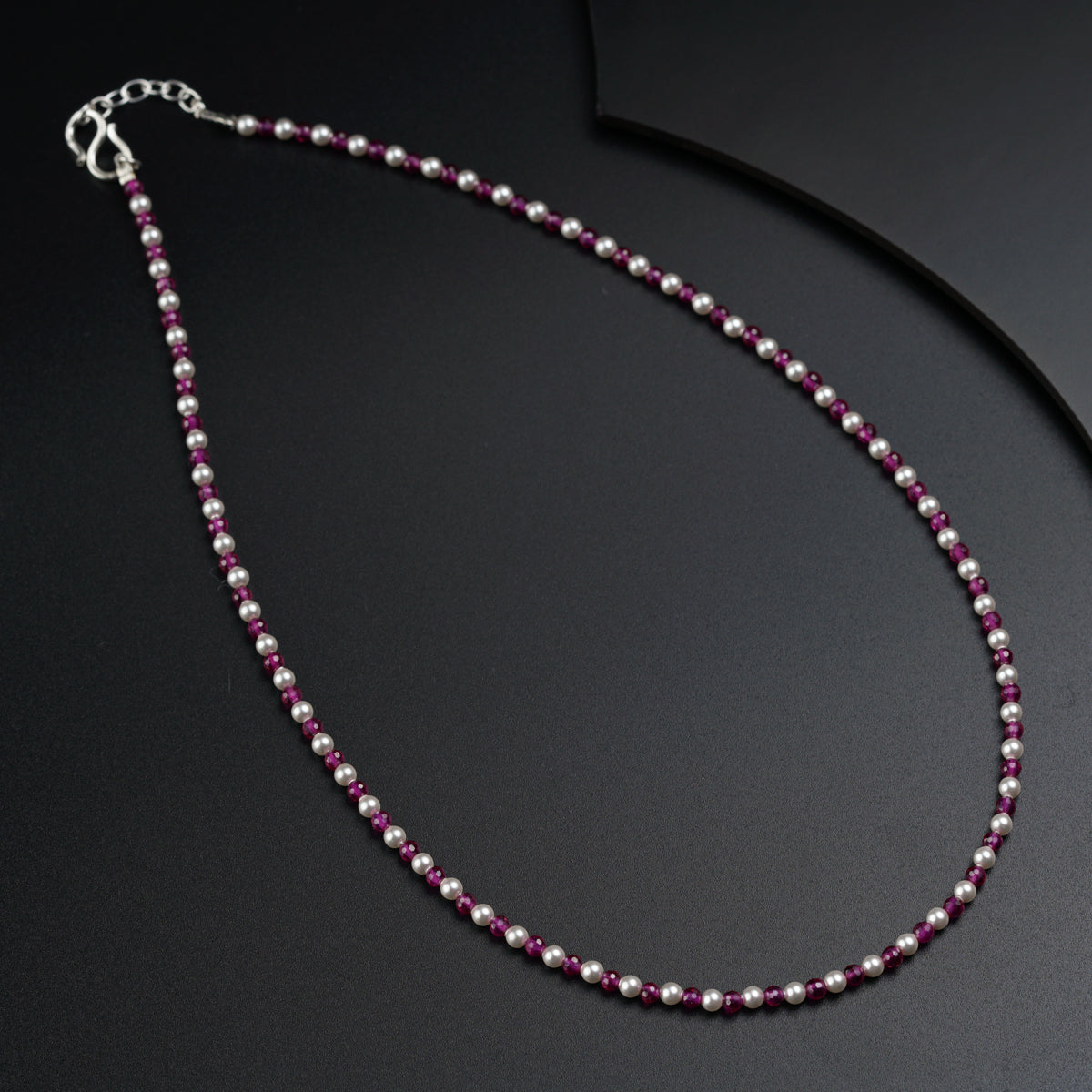 a necklace with pink beads on a black surface