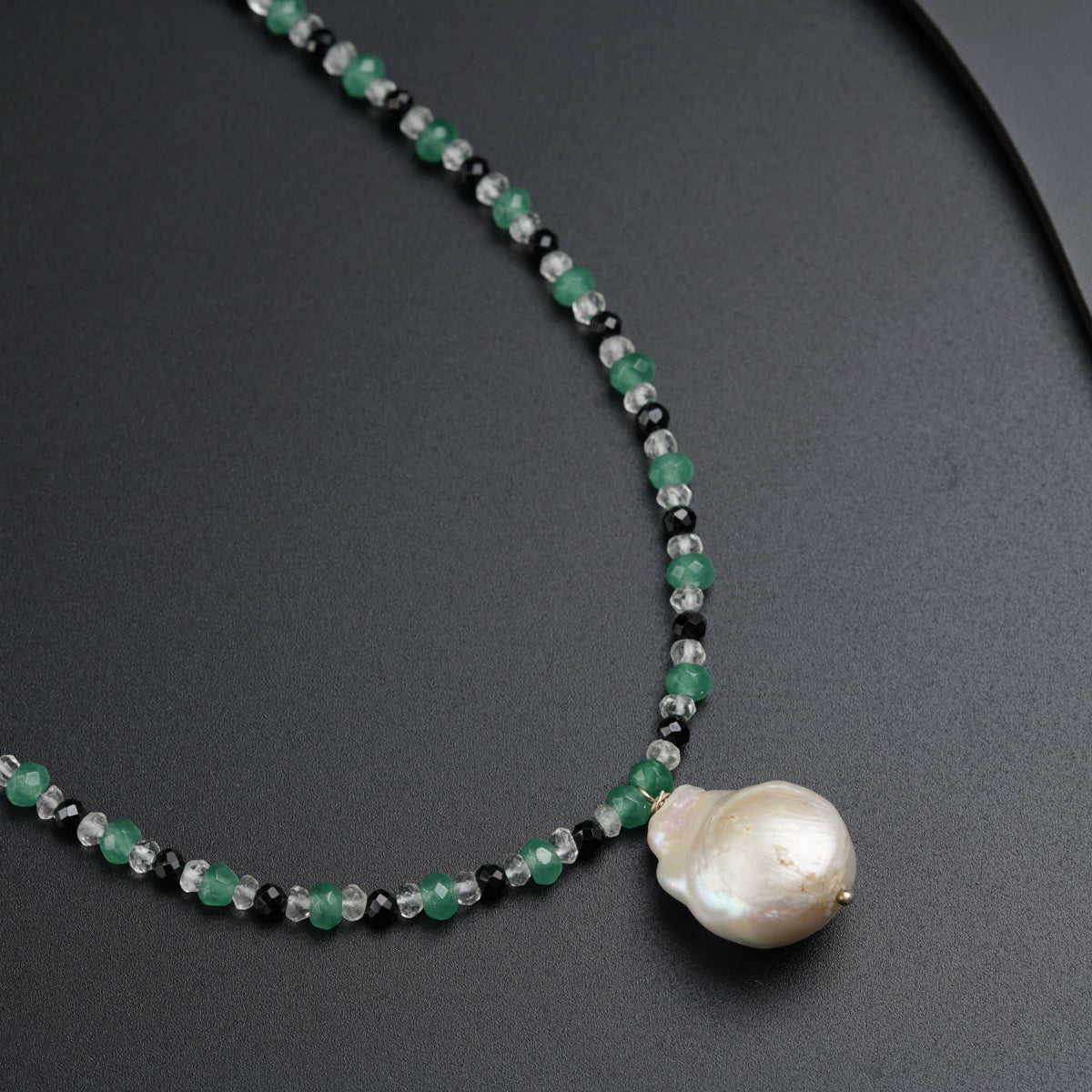 a necklace with a pearl and green beads