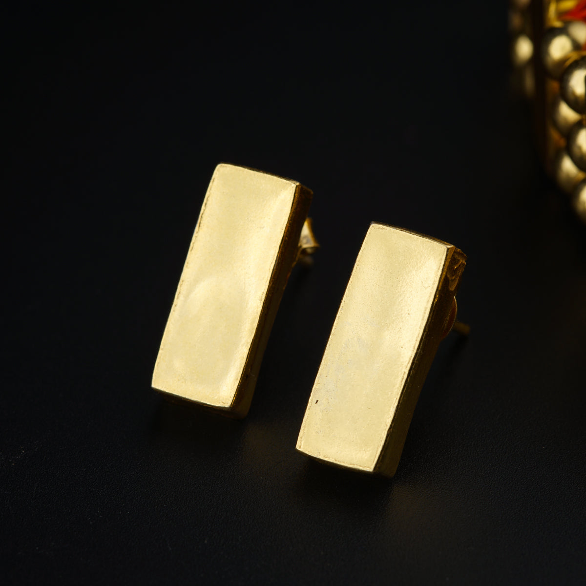 a pair of gold earrings sitting on top of a table
