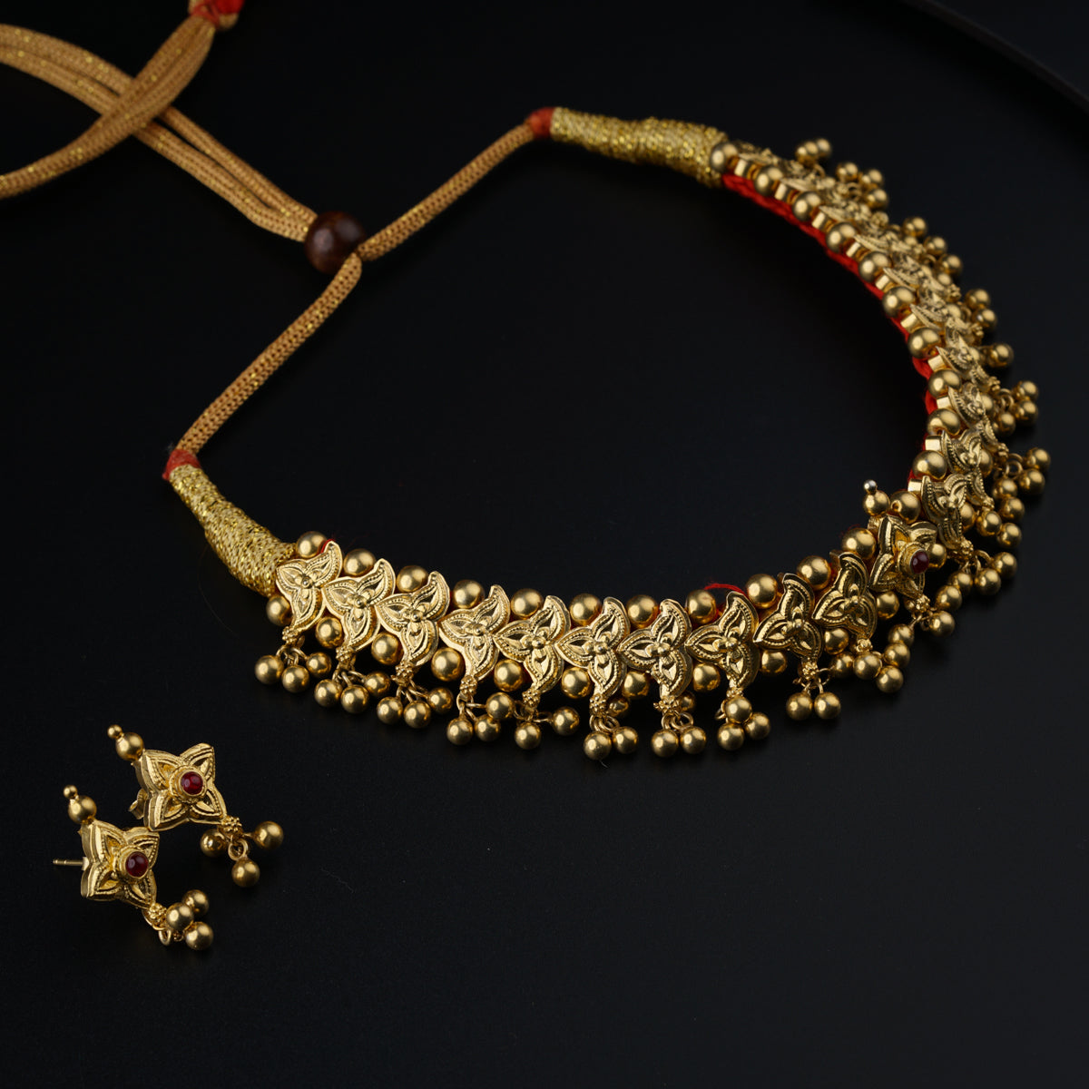 a gold necklace and earrings on a black surface