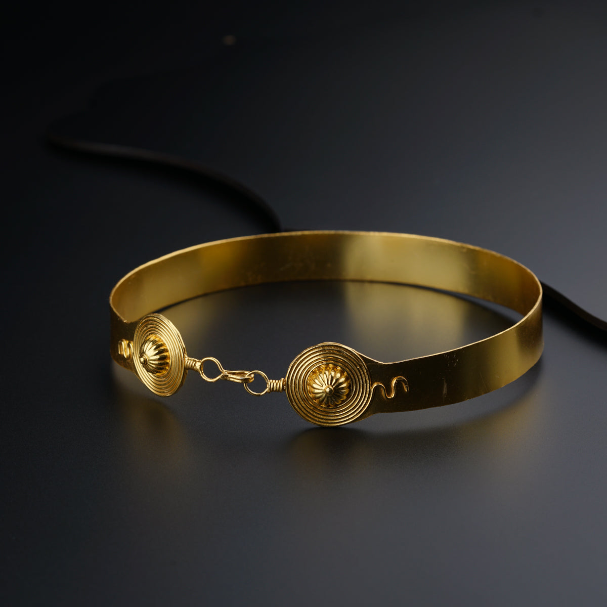 a close up of a gold bracelet on a black surface