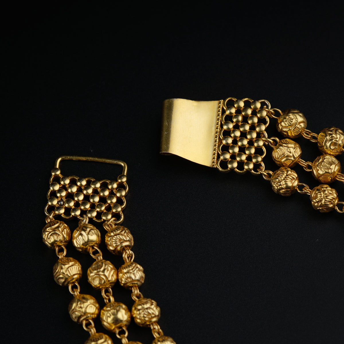 a pair of gold bracelets on a black surface