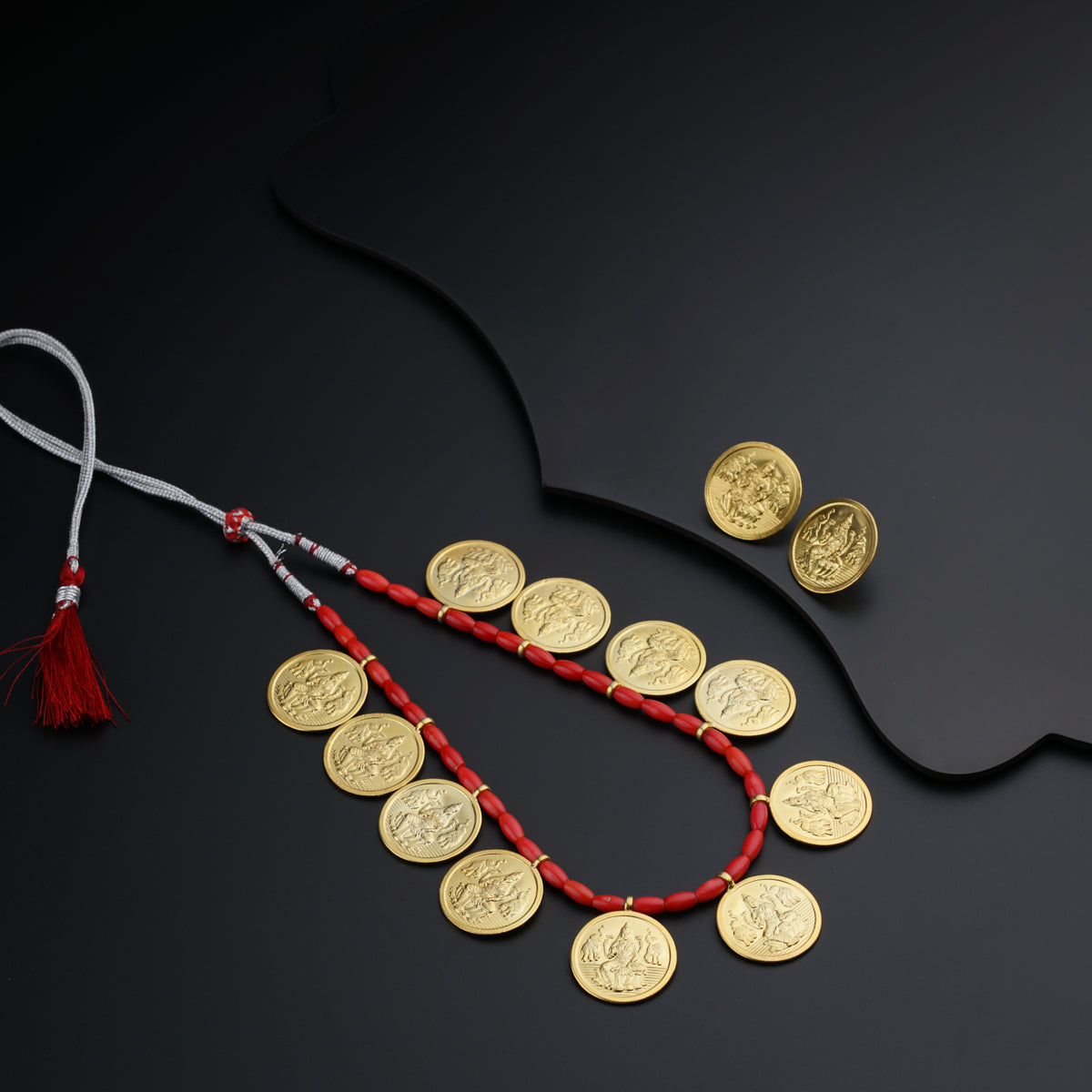a necklace with coins and a tassel on a black surface