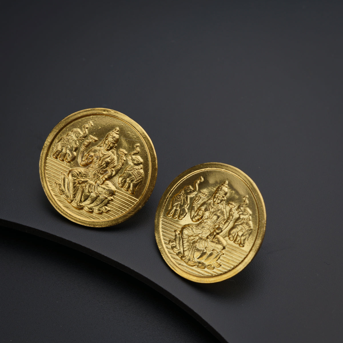 two gold coins sitting on top of a black surface