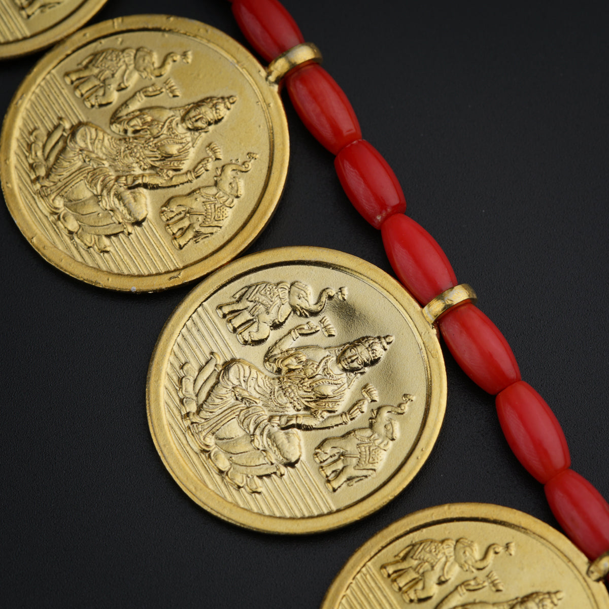a red beaded necklace with three gold coin pendants