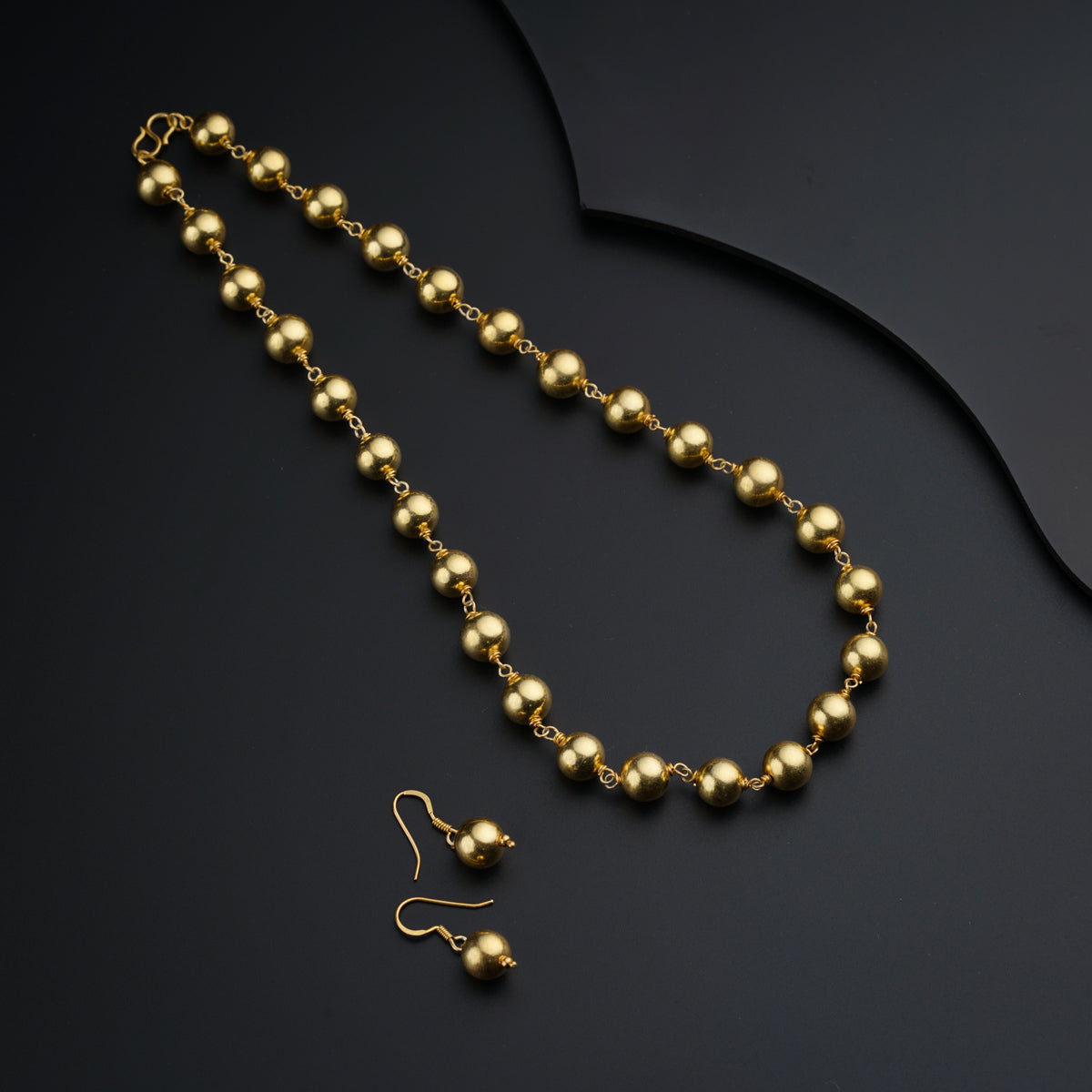 a gold beaded necklace on a black surface