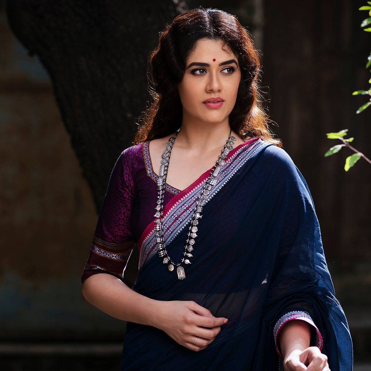 a woman wearing a blue sari and a necklace