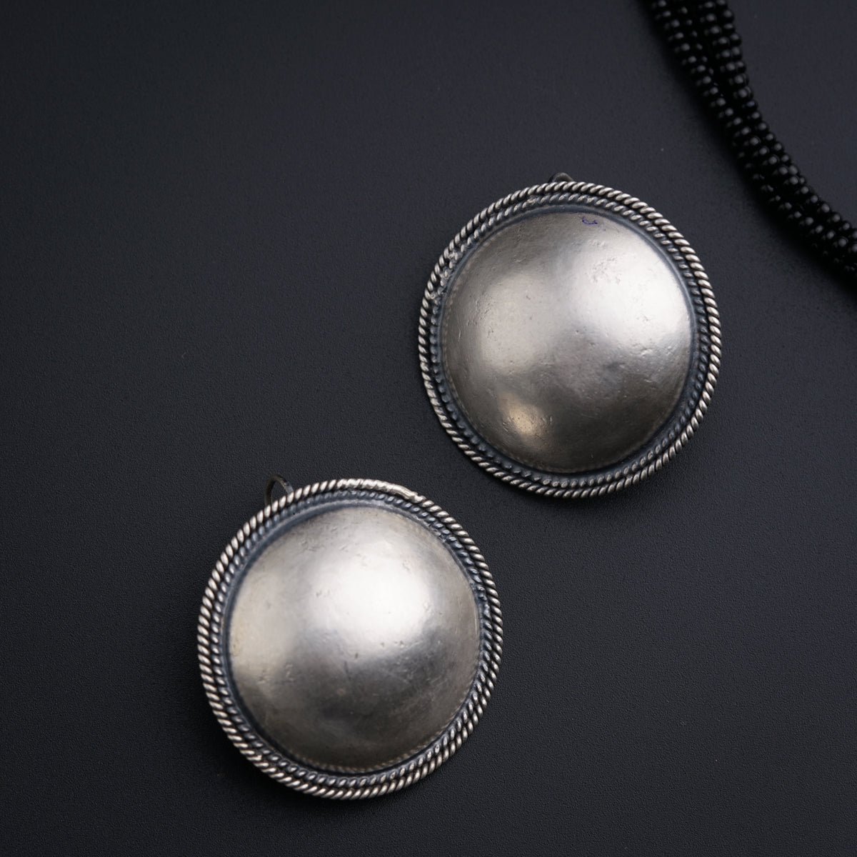 a pair of silver buttons sitting on top of a black surface