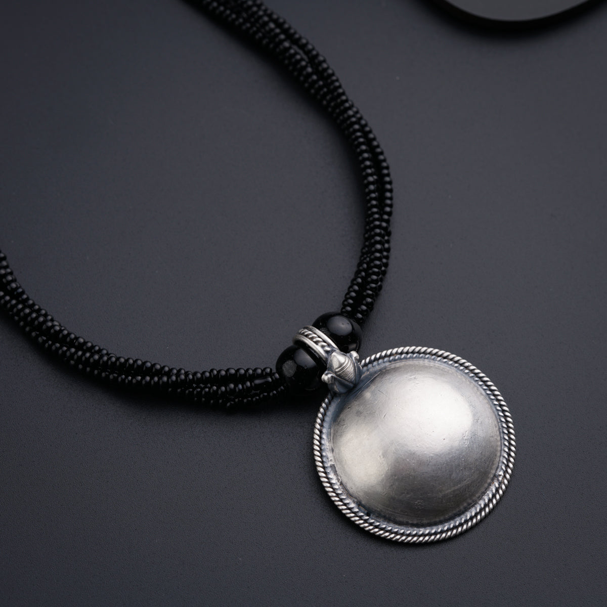 a necklace with a silver ball on a black background