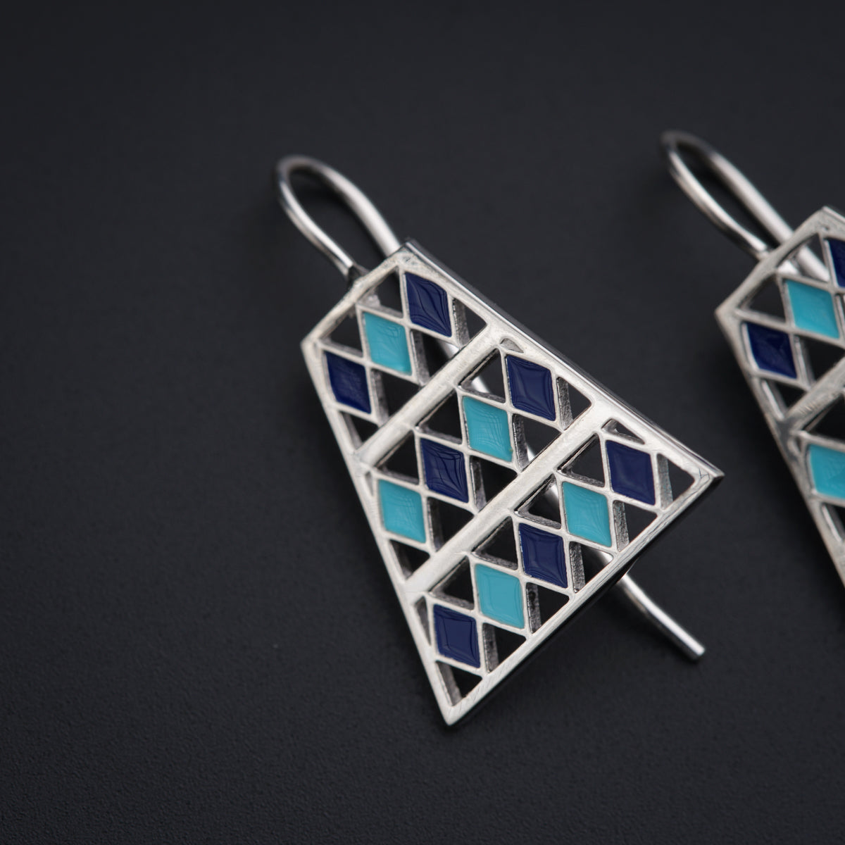 a pair of silver and blue earrings on a black surface