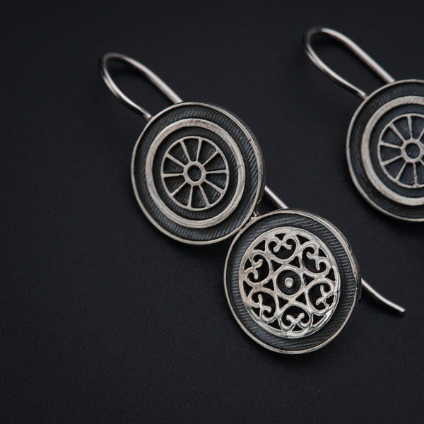 a pair of silver earrings on a black background