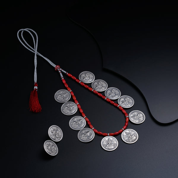 a red string with a coin and a tassel