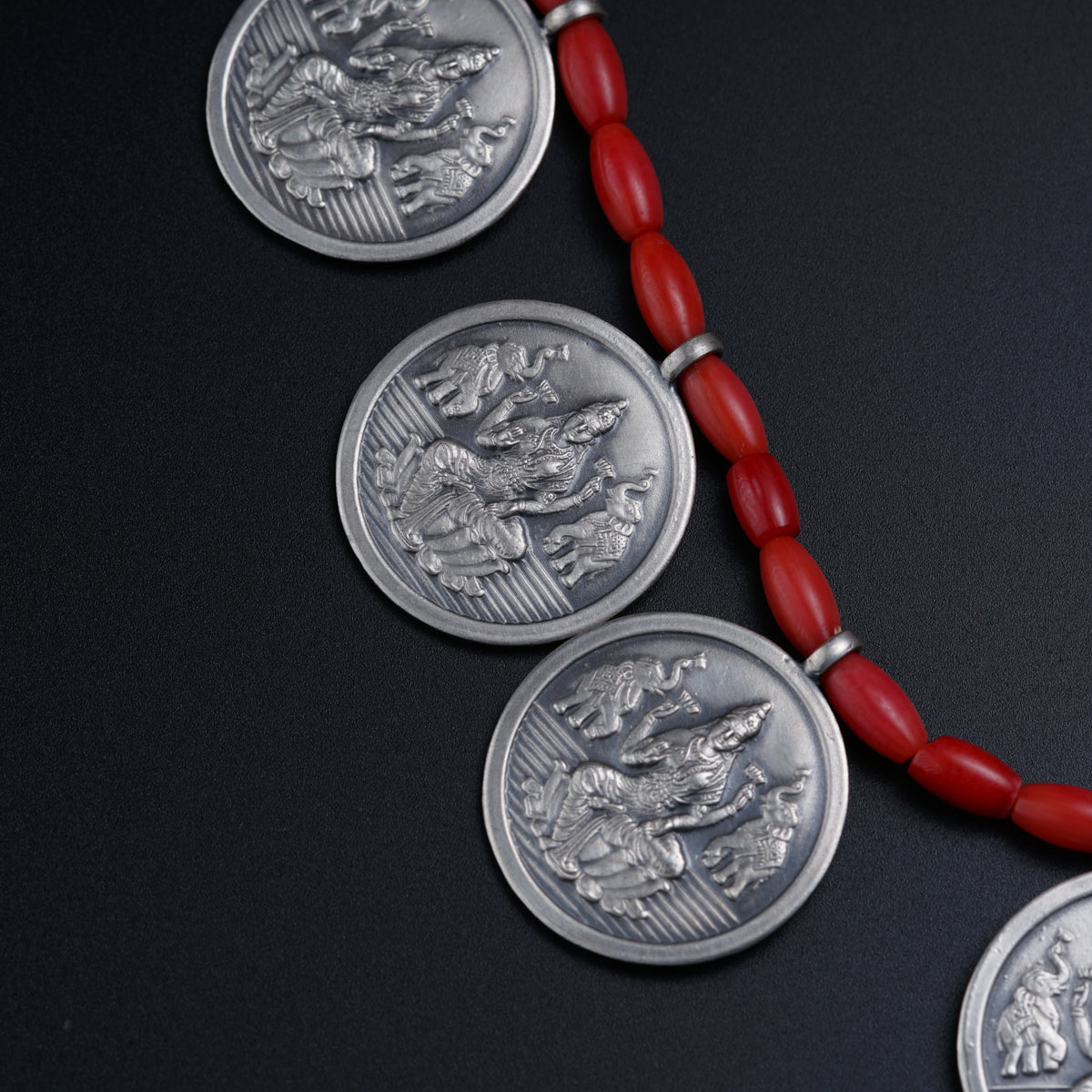 a red beaded necklace with three silver coin medallions