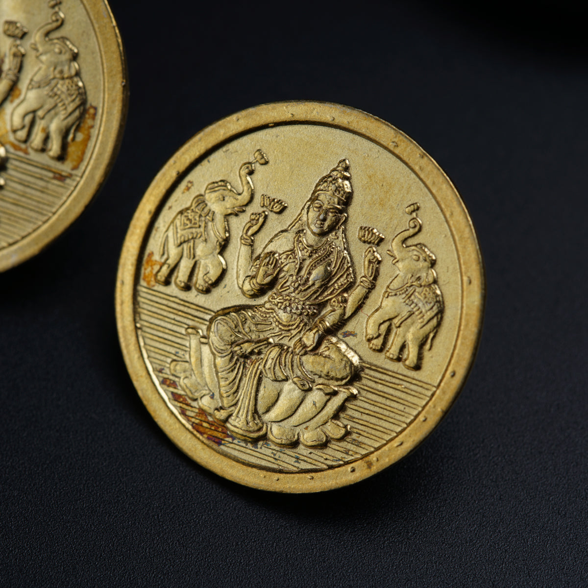 a close up of two gold coins on a black surface