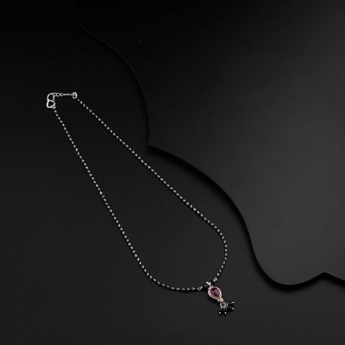 a necklace with a pink stone on a black background