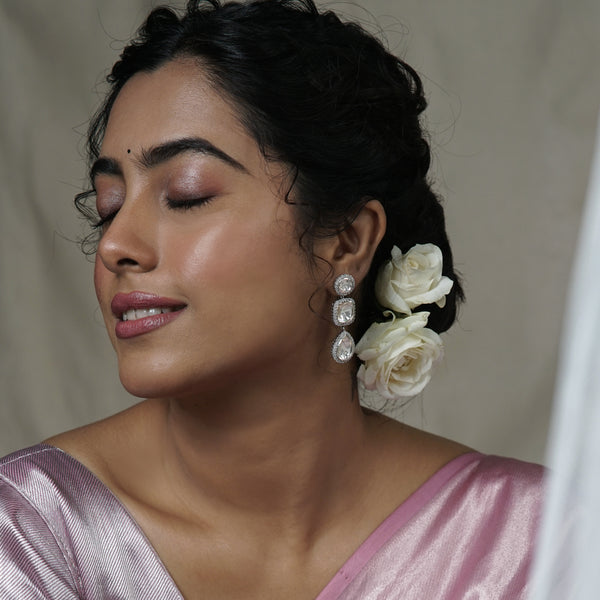 Woman wearing silver earrings with large stones and floral hair accessories