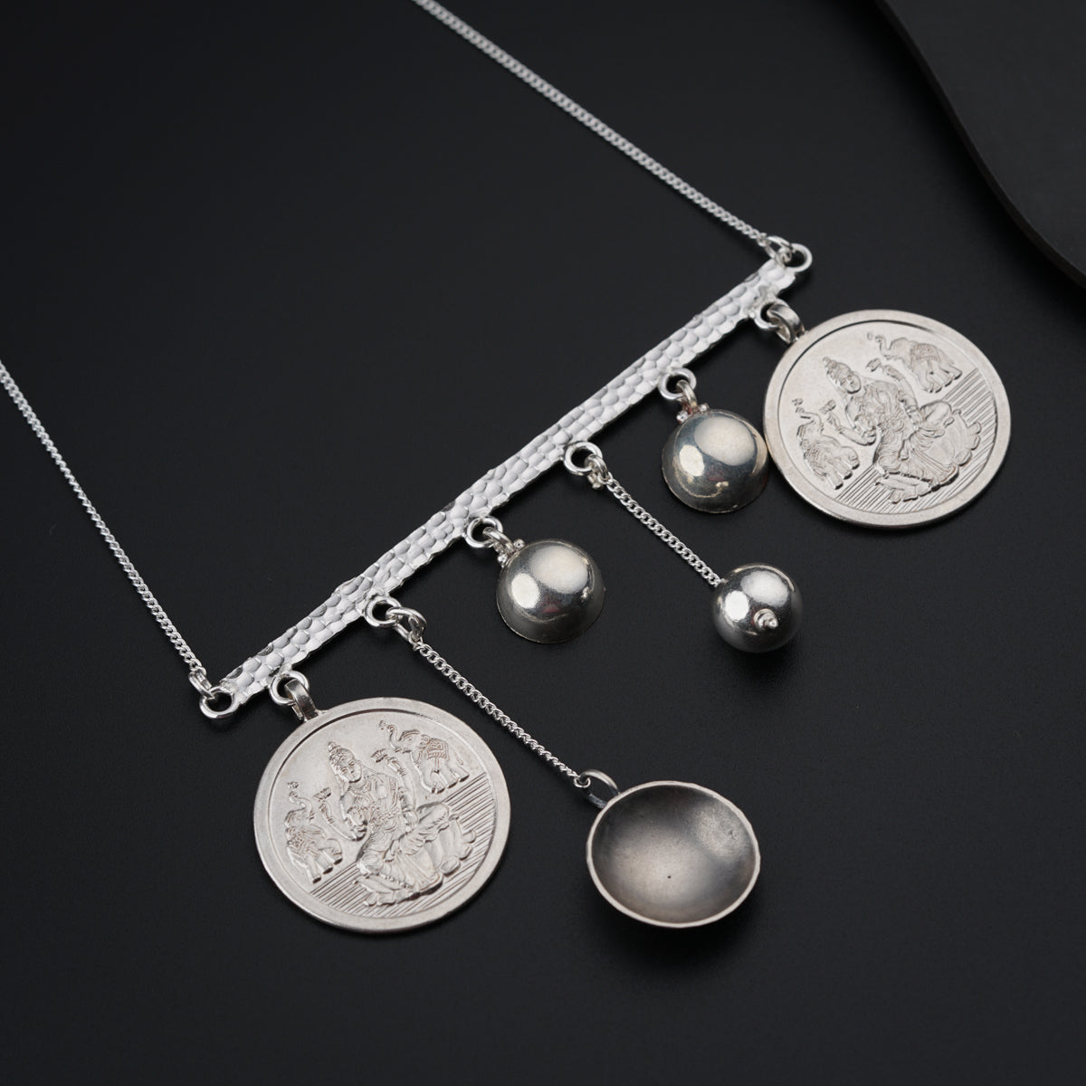a necklace with a coin and three balls on it