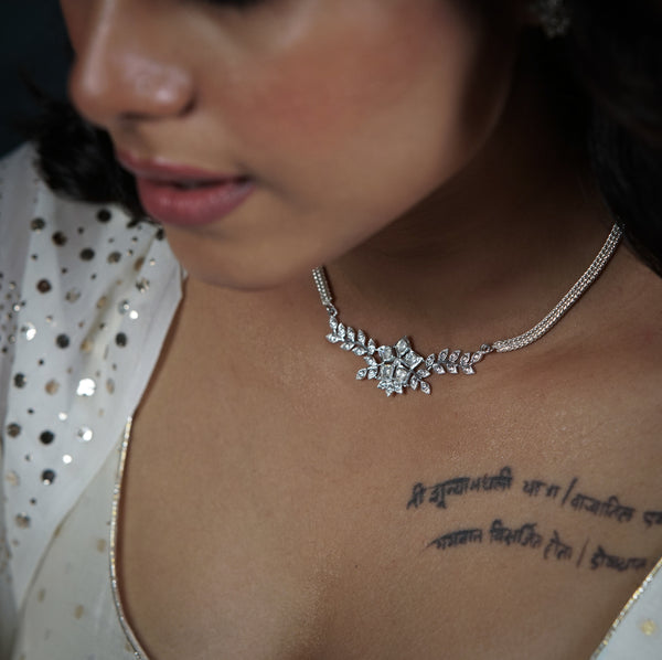 Close-up of woman wearing silver necklace with leaf and flower design, for jewelry sets