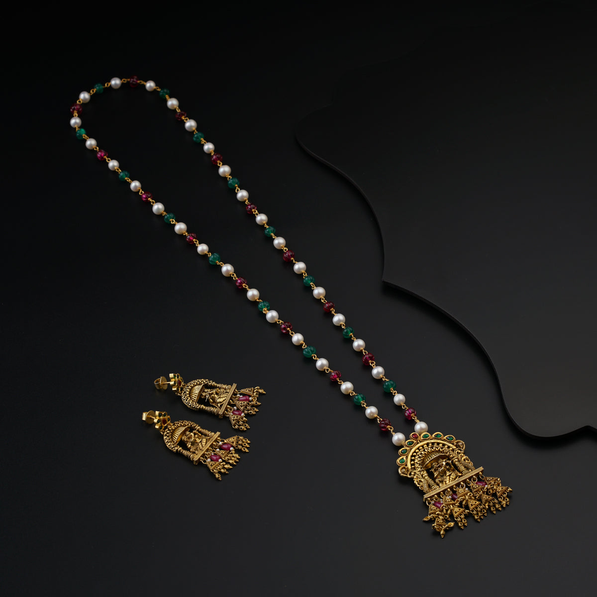 a necklace and a pair of earrings on a black surface