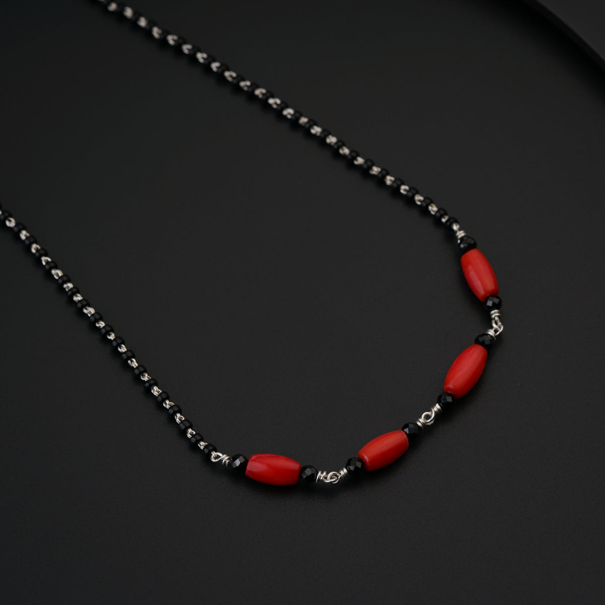 a red and black beaded necklace on a black surface
