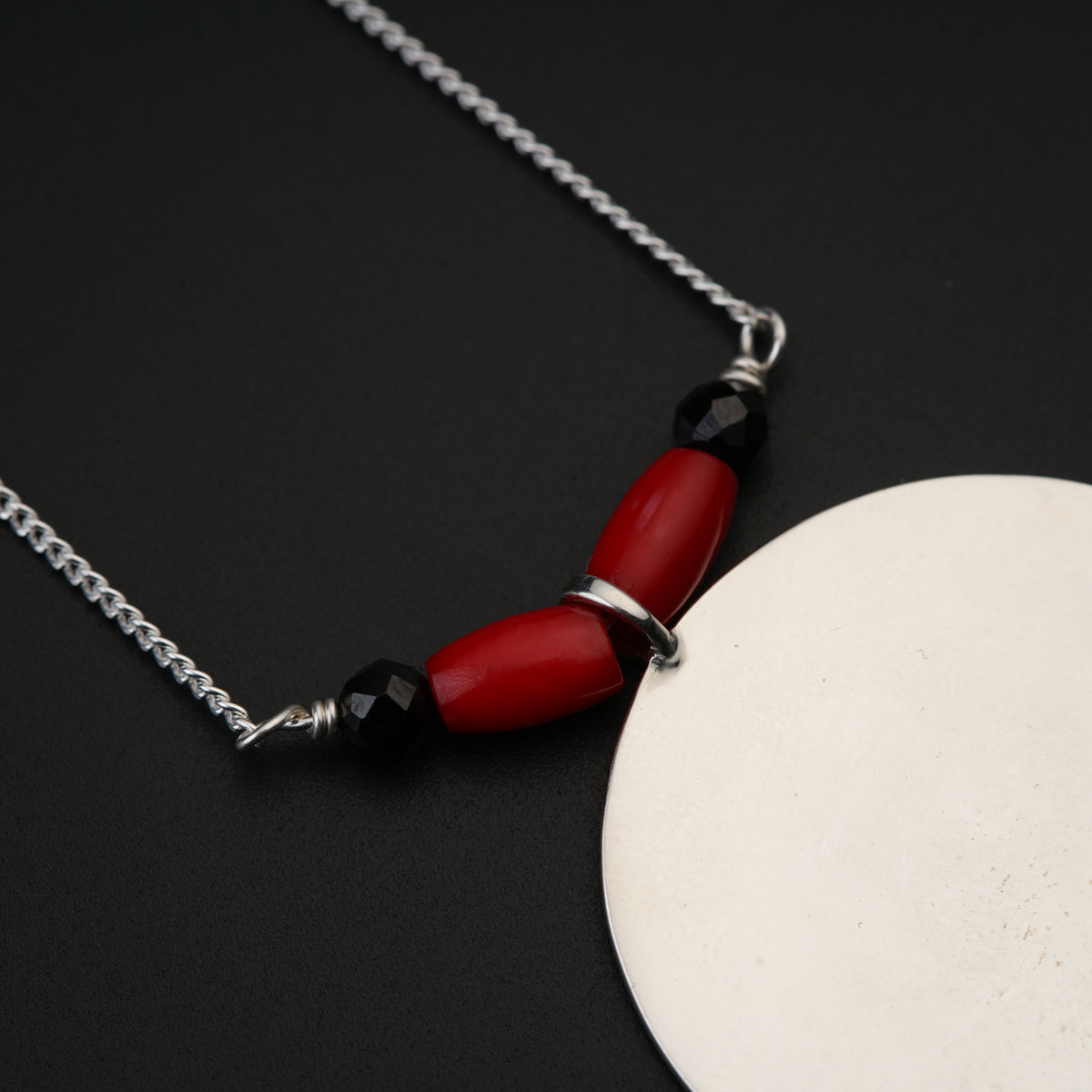 a necklace with a red bead and black beads