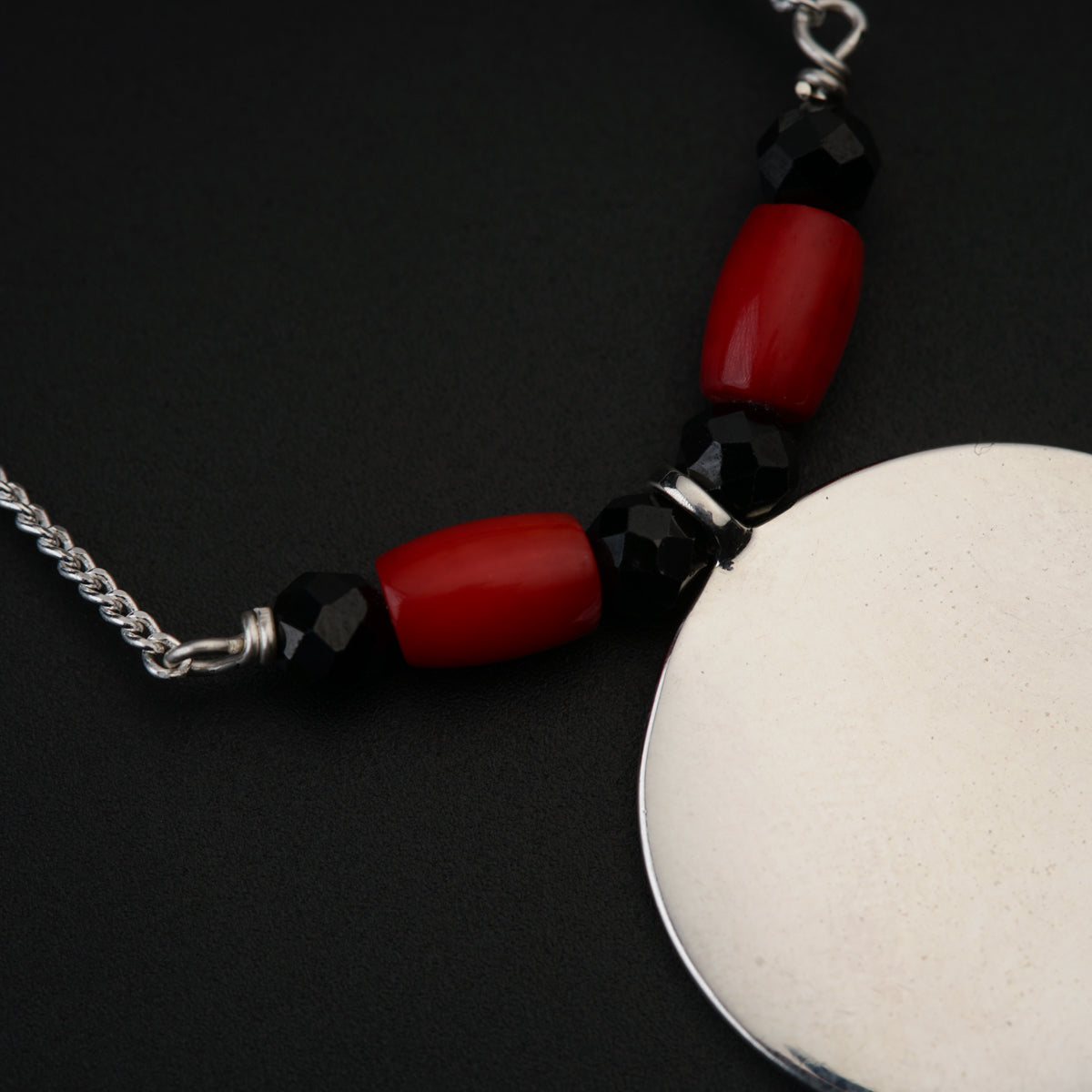 a red and black beaded necklace on a white disc