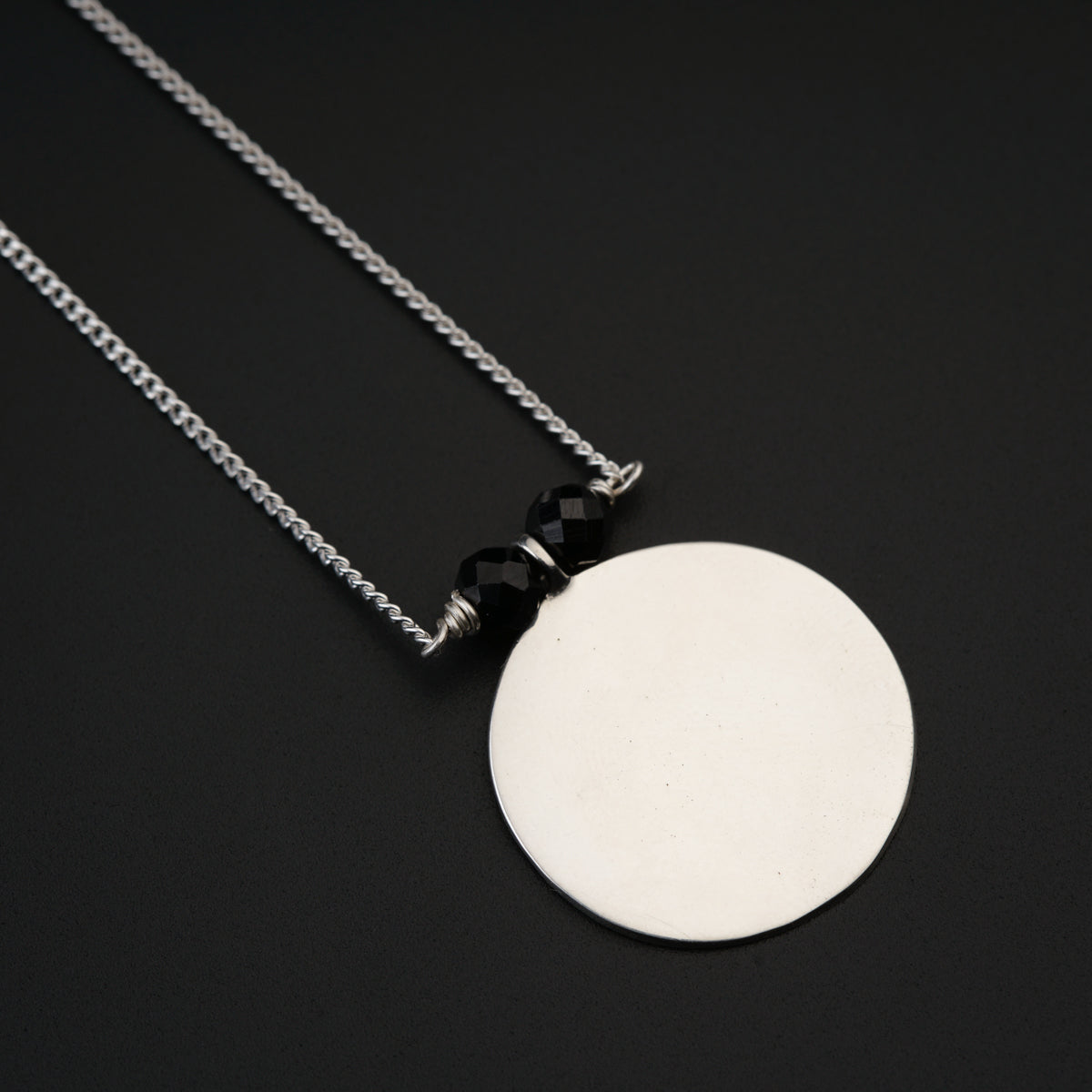 a white disc on a chain on a black surface
