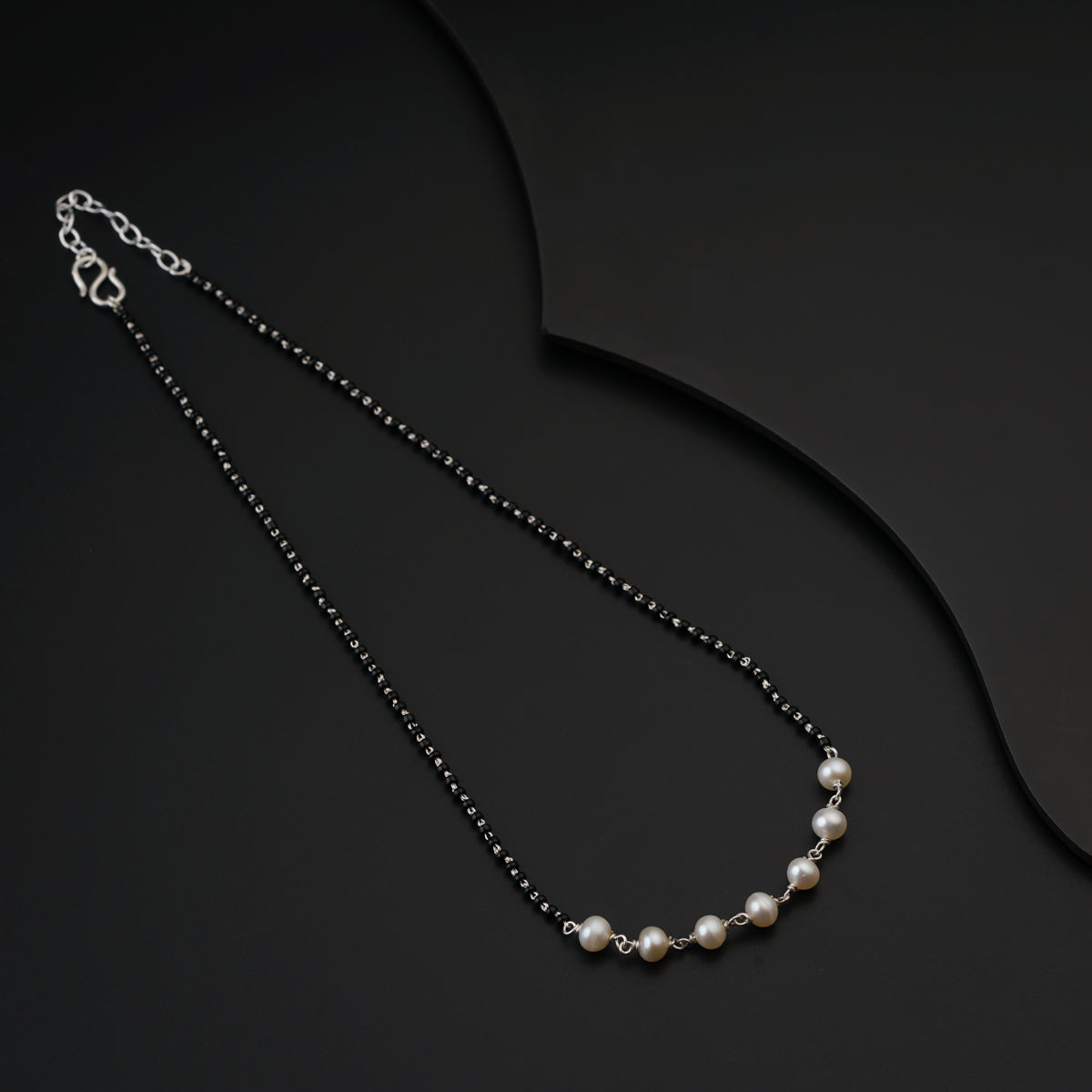 a black and white necklace with pearls on a black background