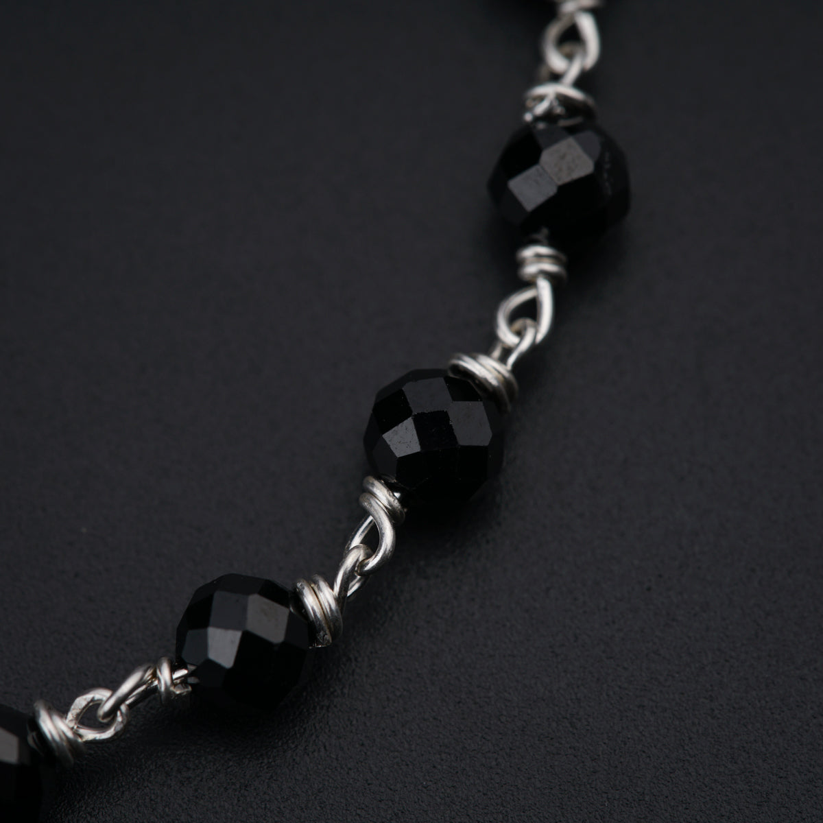 a close up of a black beaded necklace on a black surface