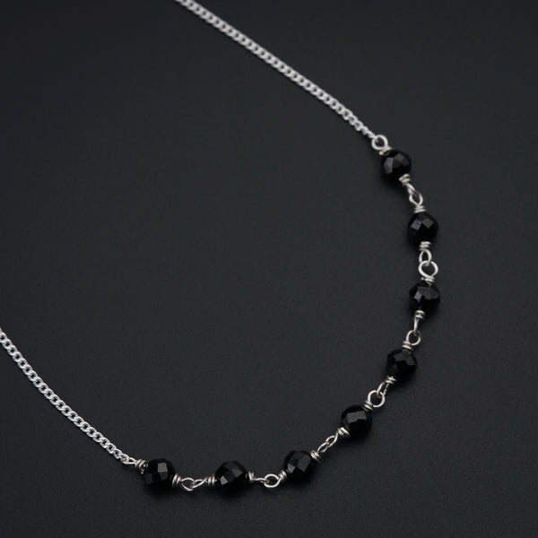 a black beaded necklace on a black surface