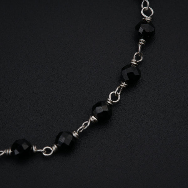 a black and silver necklace on a black surface